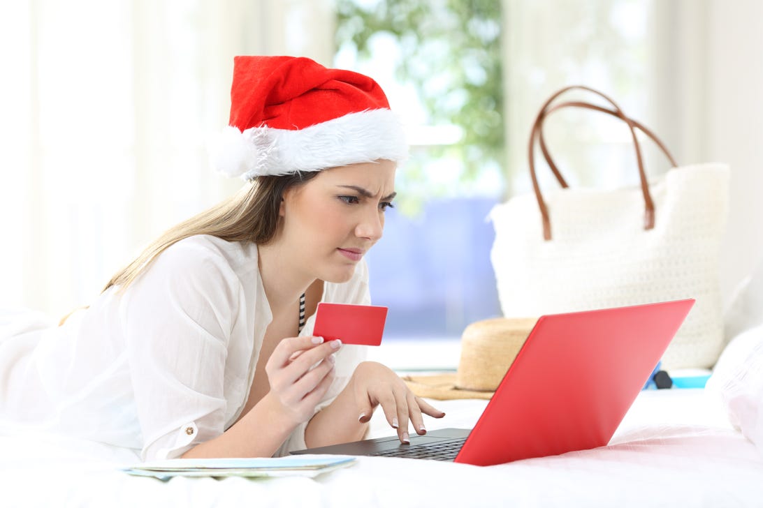 Person, wearing a Santa cap, at a laptop with a credit card