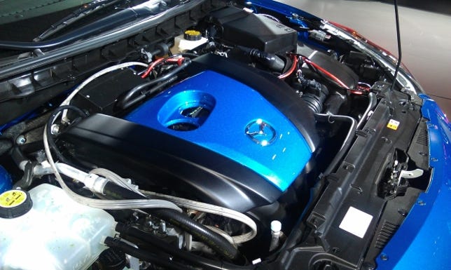 Beneath this bright blue engine cover is the new direct-injected SkyActiv-G engine.