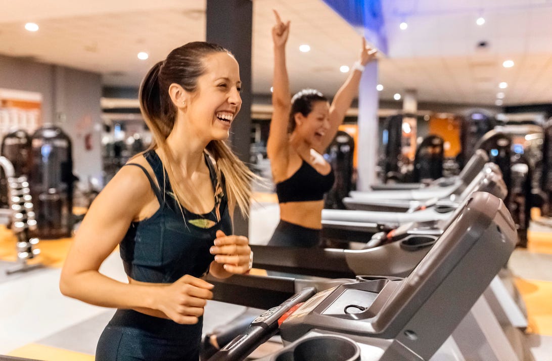 Two happy women working out in gym on a treadmill