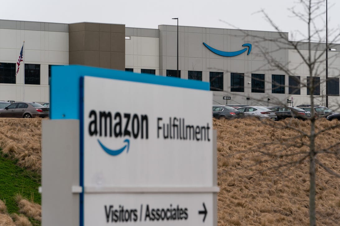 A sign says "Amazon Fulfillment" outside a warehouse with the Amazon Smile logo on it.