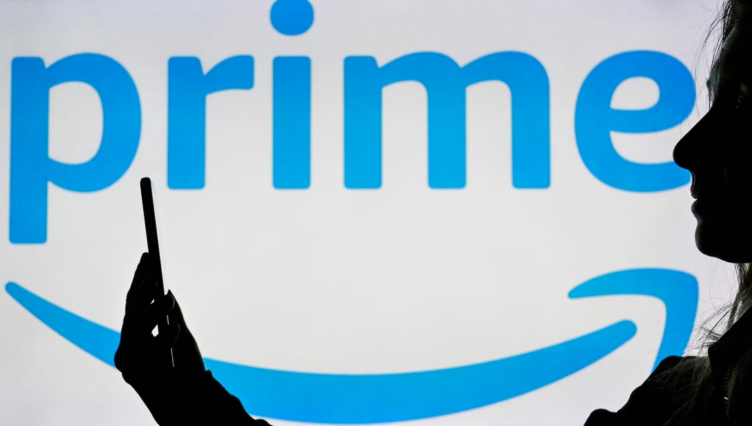 The Amazon Prime logo superimposed with the silhouette of a person looking at their smartphone in profile.