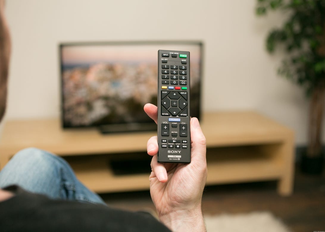A Sony remote with a TV in the background.