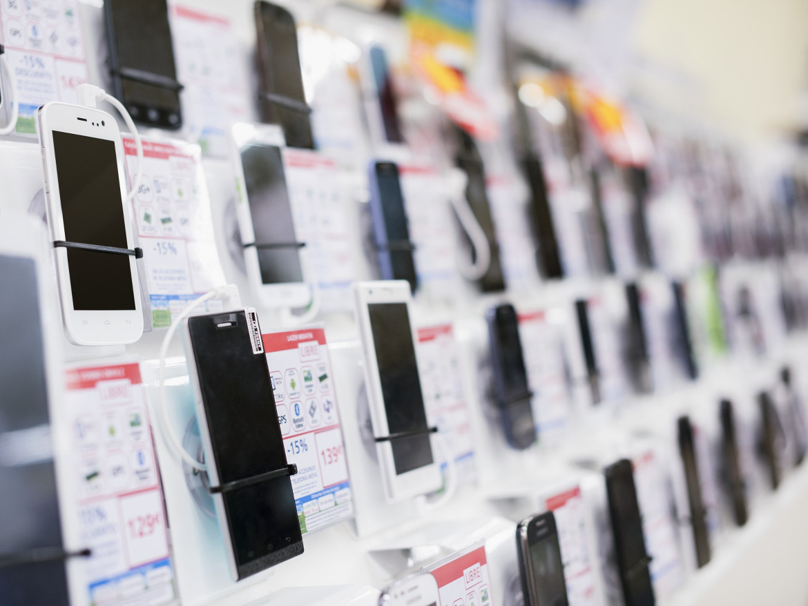 Many different smartphones on display at a retailer.