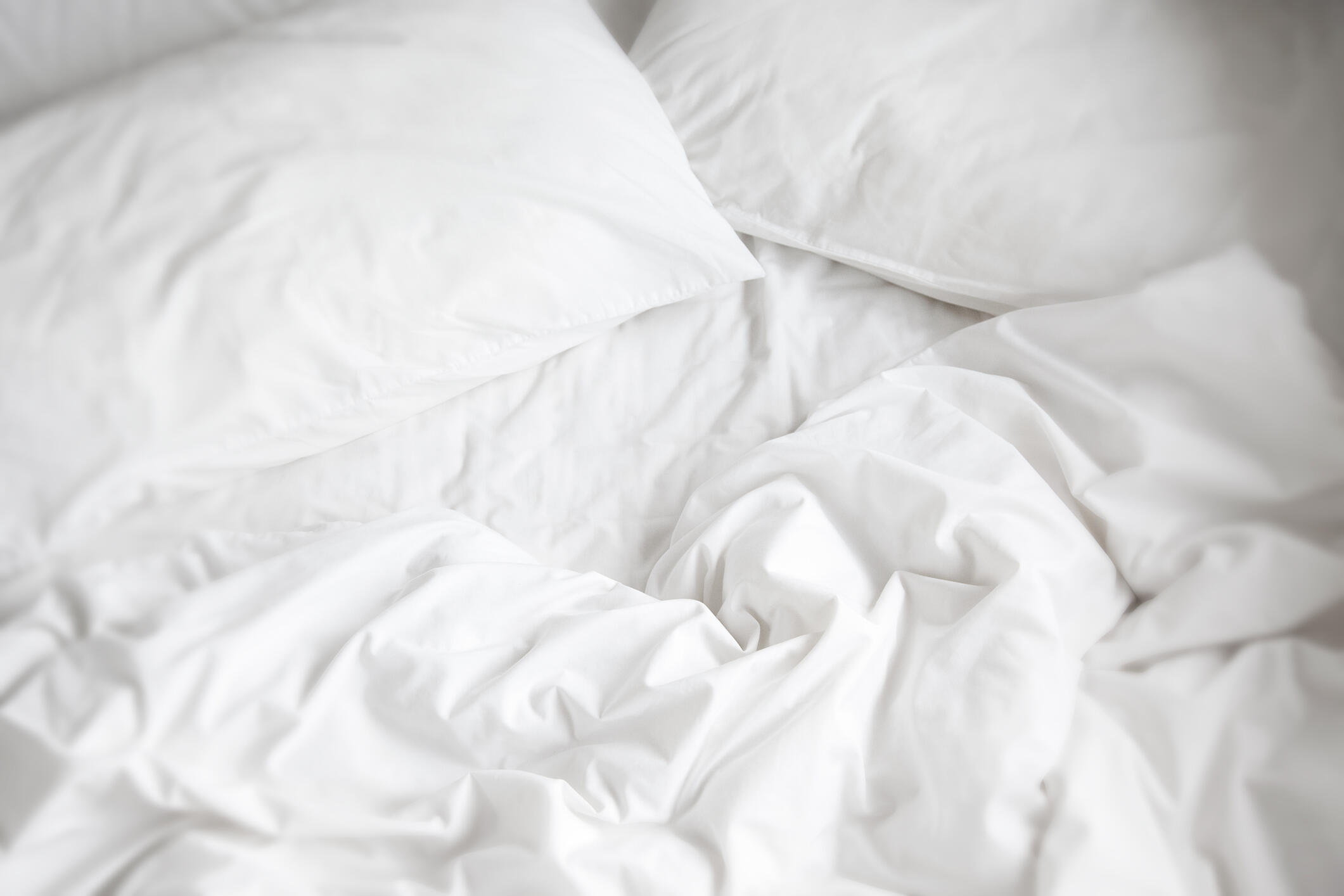 A pair of clean white sheets, a comfy white comforter and fluffy pillows.