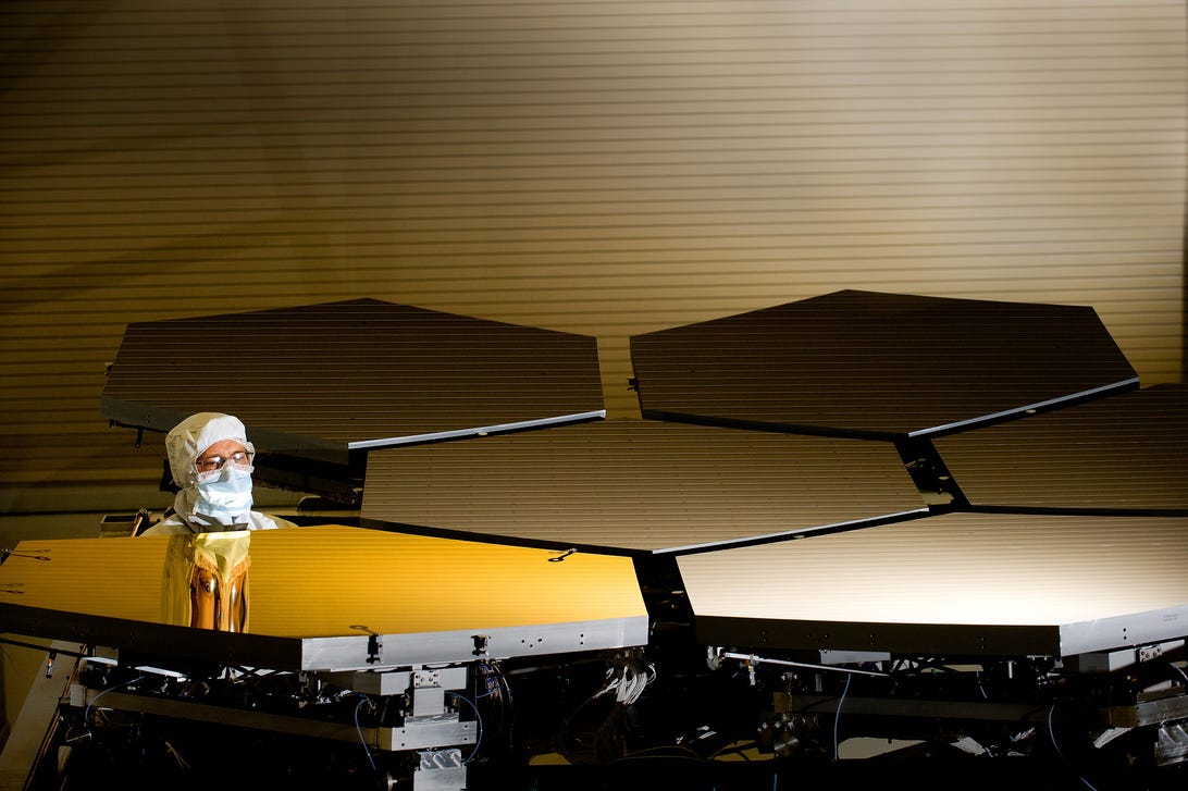 A technician inspects a mirror segment of the James Webb Space Telescope