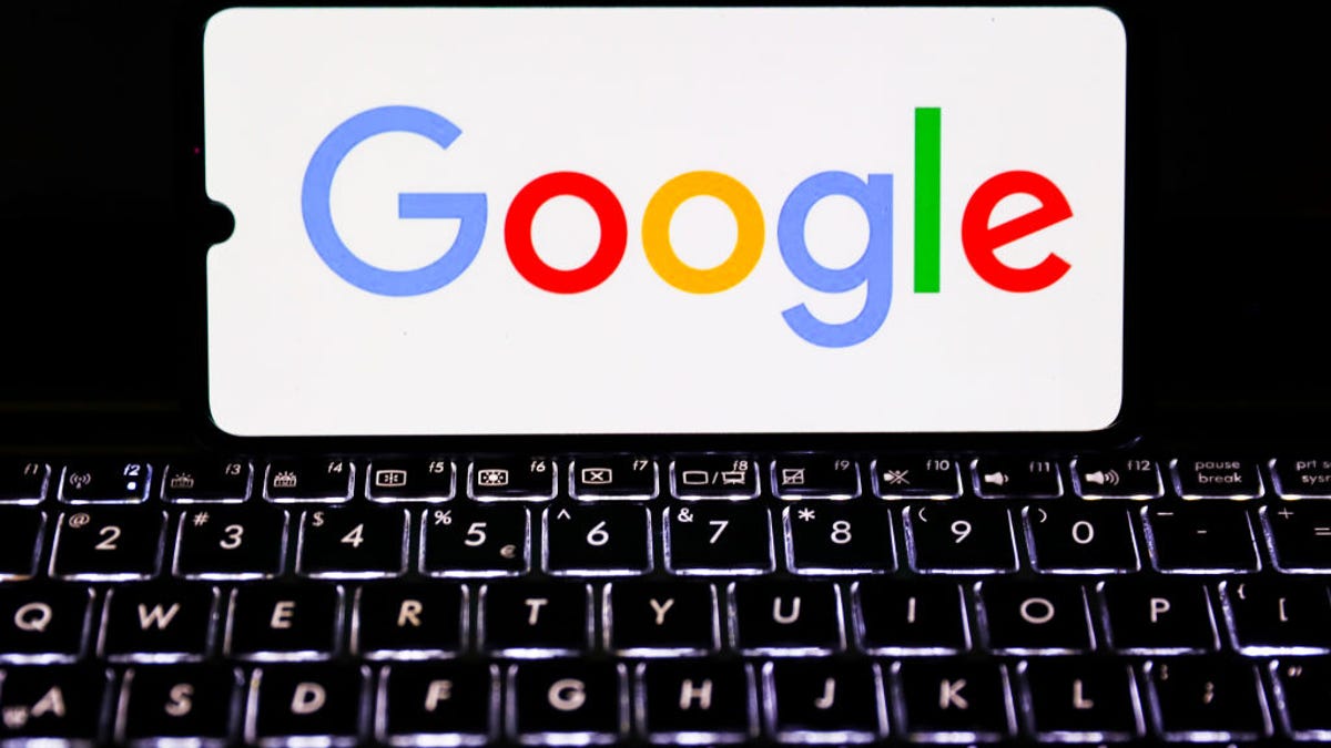Google logo on a phone screen above a keyboard.