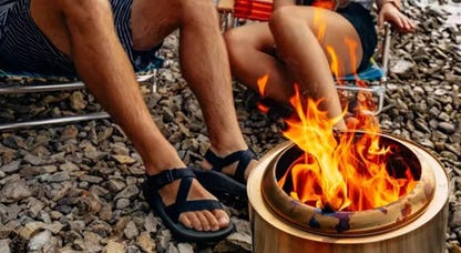 Solo Stove's Ranger is displayed near two people wearing shorts and flip flops.