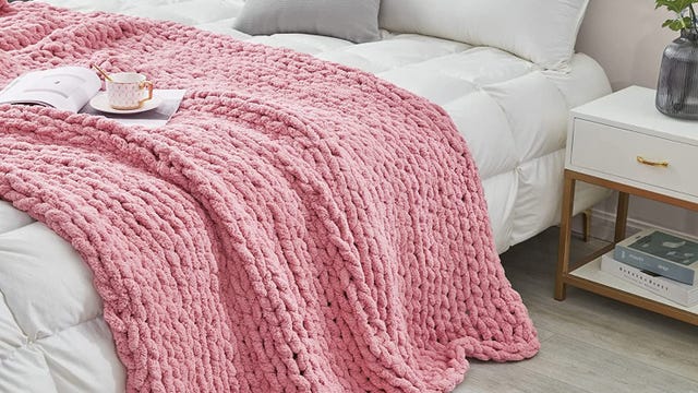 Pink blanket thrown over a white bed