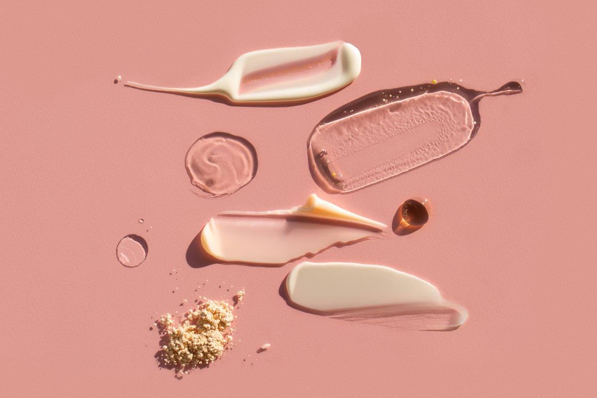 Druppels en uitstrijkjes van verschillende cosmetische producten op roze achtergrond