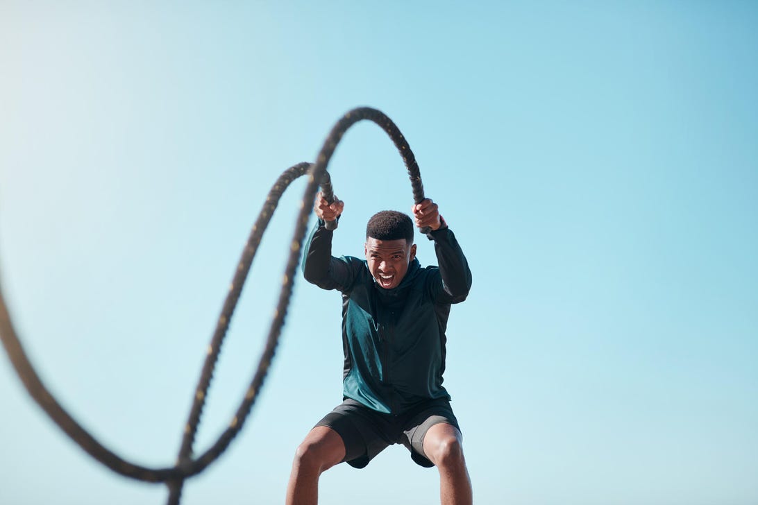 a young man doing high intensity exercise with battle ropes outdoors