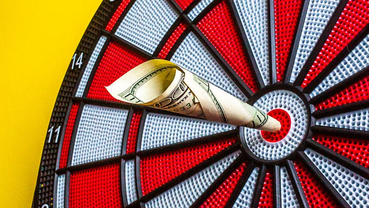 A rolled-up $100 bill in the bull's-eye of a dartboard