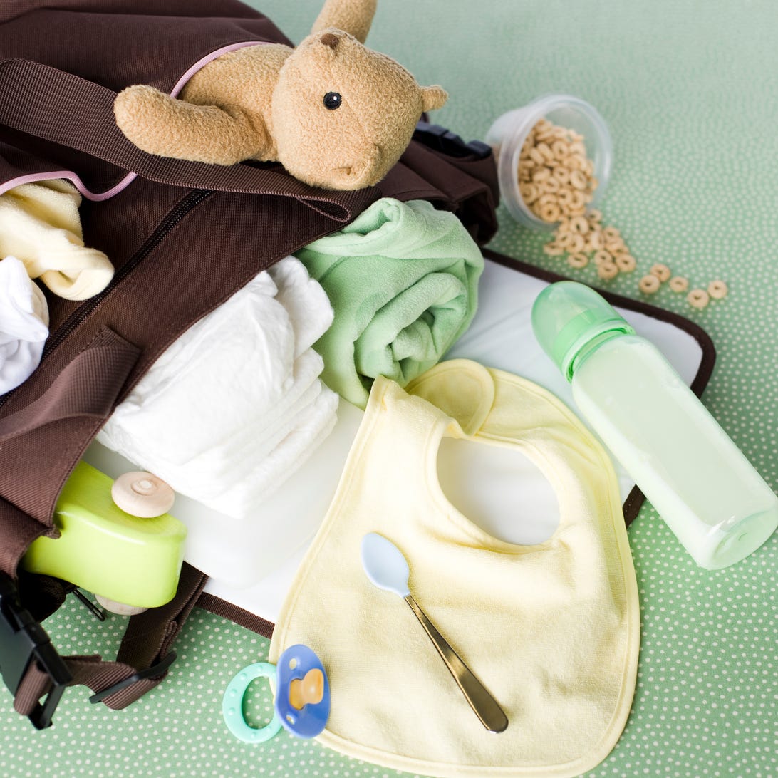 a bottle, pacifier, bib and other baby items spill out of a diaper bag