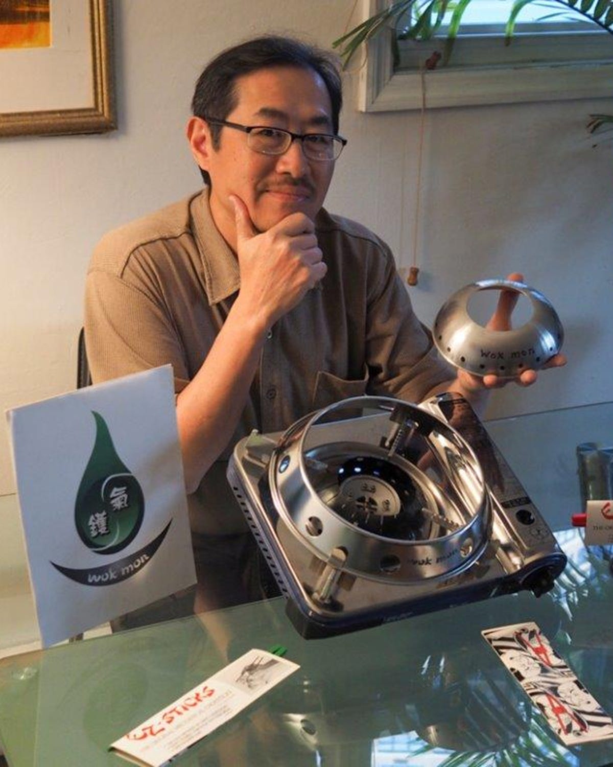 Glen Lee, the inventor of the WokMon poses with his invention and a portable burner. The secret is a focusing ring that concentrates flames from a gas range into one area.