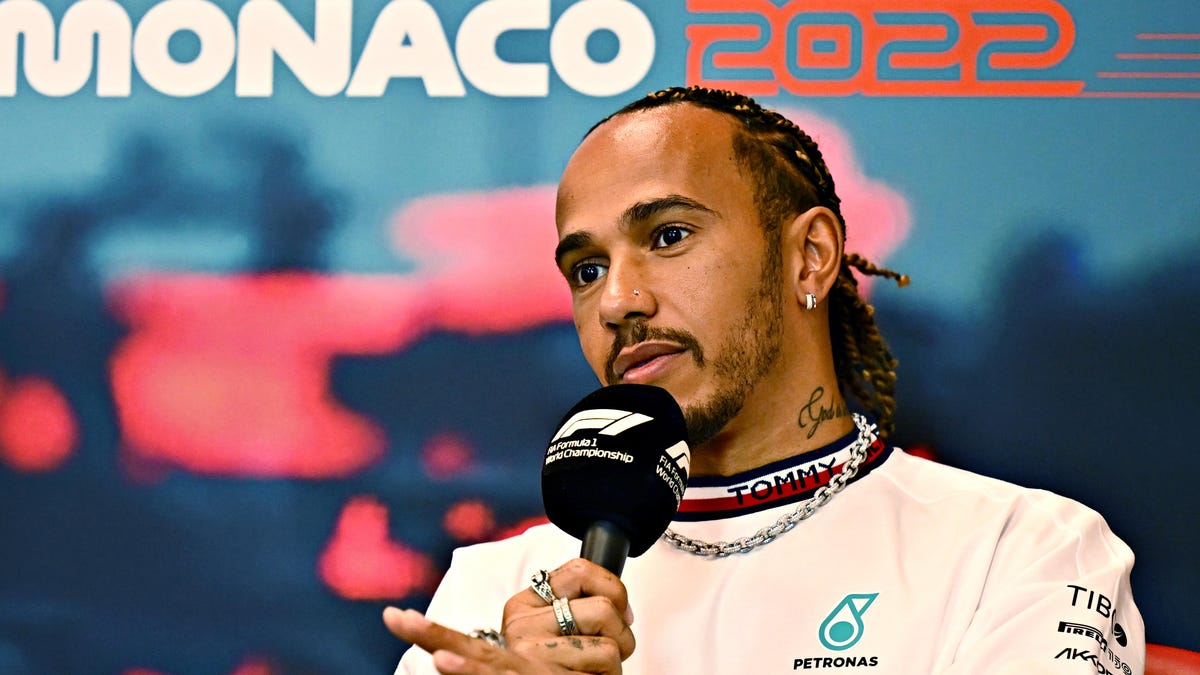 Lewis Hamilton speaks into a mic in front of a Monaco 2022 sign