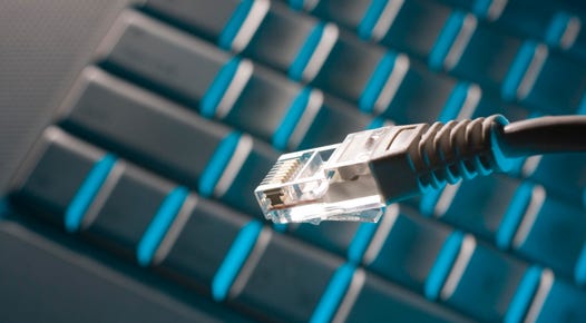 Stock photo of an ethernet cable with a blurred keyboard in the background.