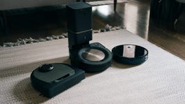 Three robot vacuum cleaners lined up on a white rug