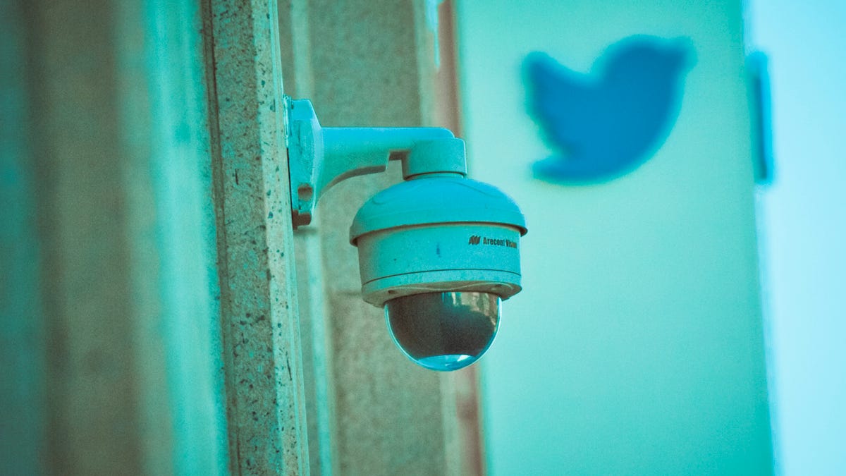 A security camera attached to the building that houses Twitter headquarters in San Francisco, with the Twitter logo in the background.