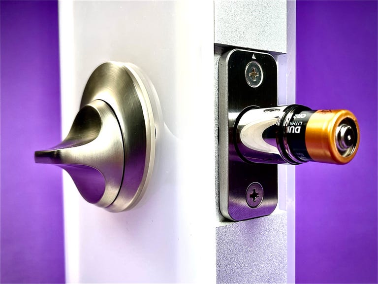 The Level Lock Plus installed in a display door, with the deadbolt extended. The tip of the deadbolt is unscrewed and removed, revealing a single CR2 battery inside that keeps the thing powered.