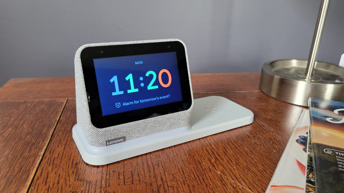A Lenovo smart clock and charging dock on a wooden table. 
