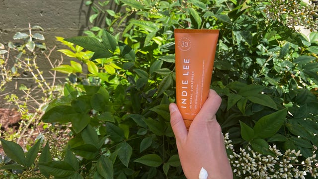A hand holding Indie Lee Mineral Sunscreen