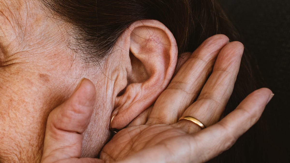 A woman cupping her ear in order to hear better