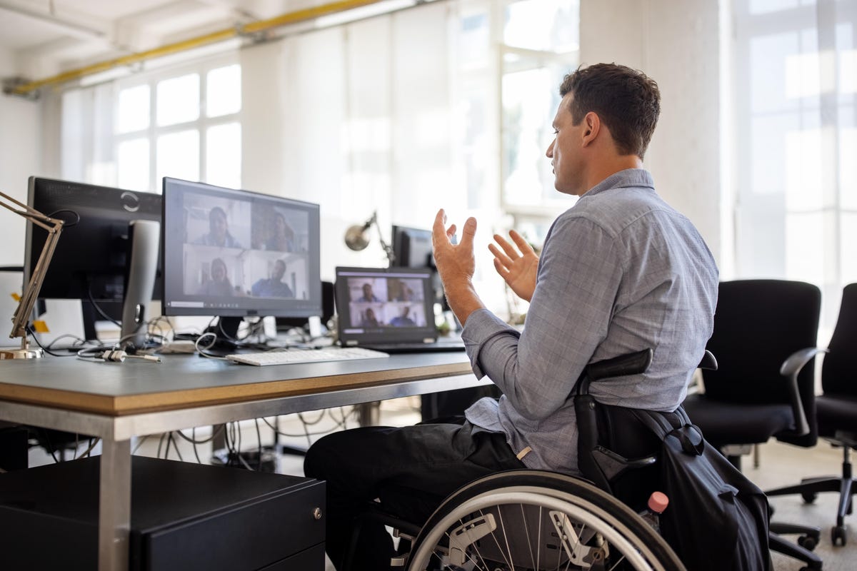 Man in wheelchair using videoconferencing on computer