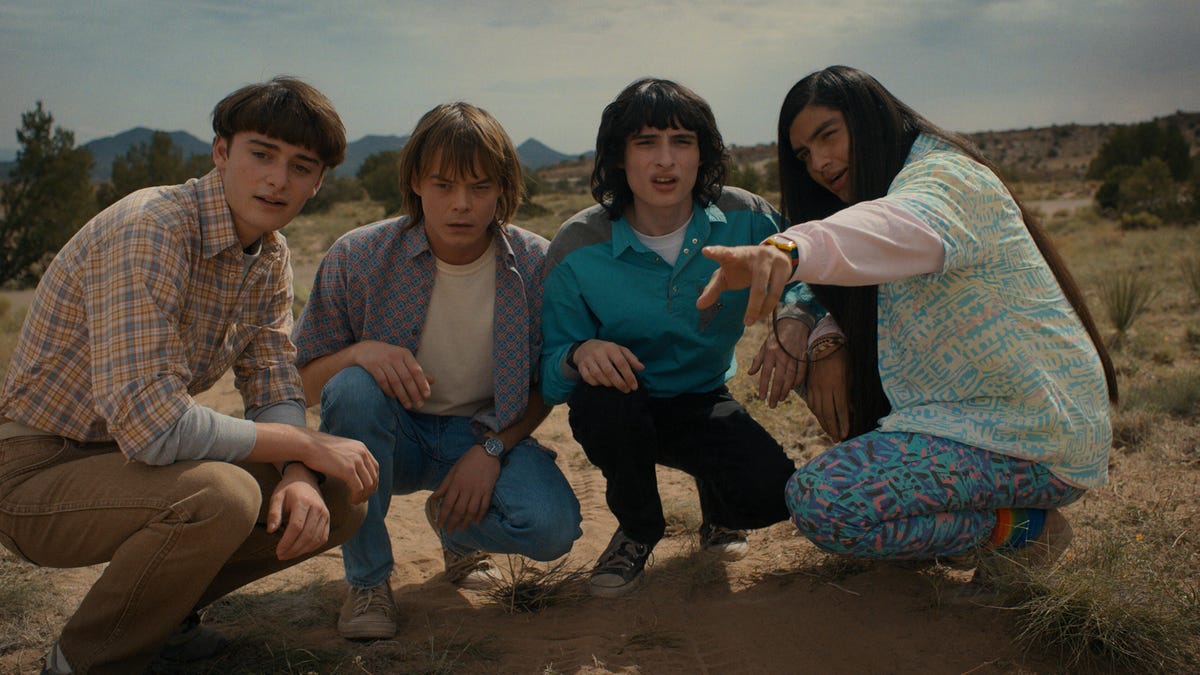Four 1980s teens crouch in the desert in Netflix series Stranger Things.