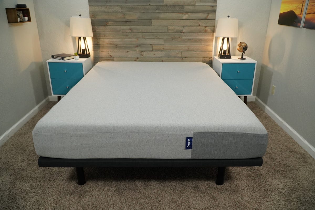 A Casper mattress on a bed frame in a brightly lit bedroom.