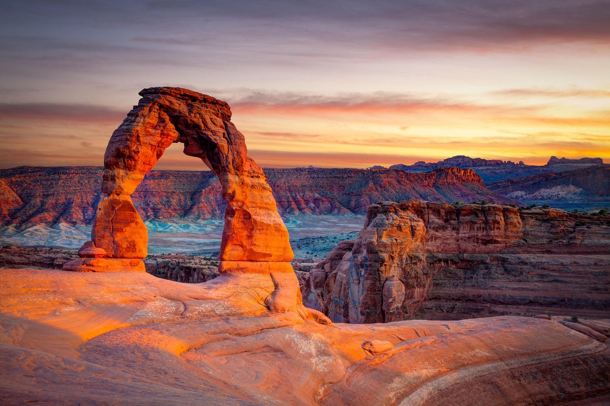 Delicate Arch, glowing in the sunrise, in Arches National Park in Utah.