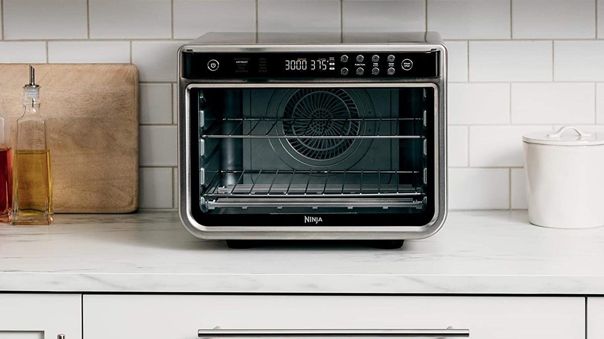 A black and silver Ninja Foodi toaster oven on a white kitchen countertop.