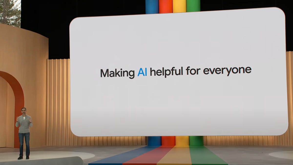 Google CEO Sundar Pichai presenting at the Google I/O keynote with a screen behind reading "Making AI helpful for everyone"