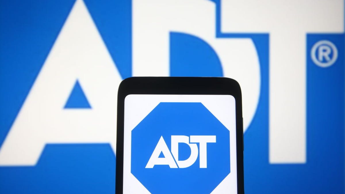 Photo illustration of the ADT logo on a smartphone in front of the ADT logo in the background.
