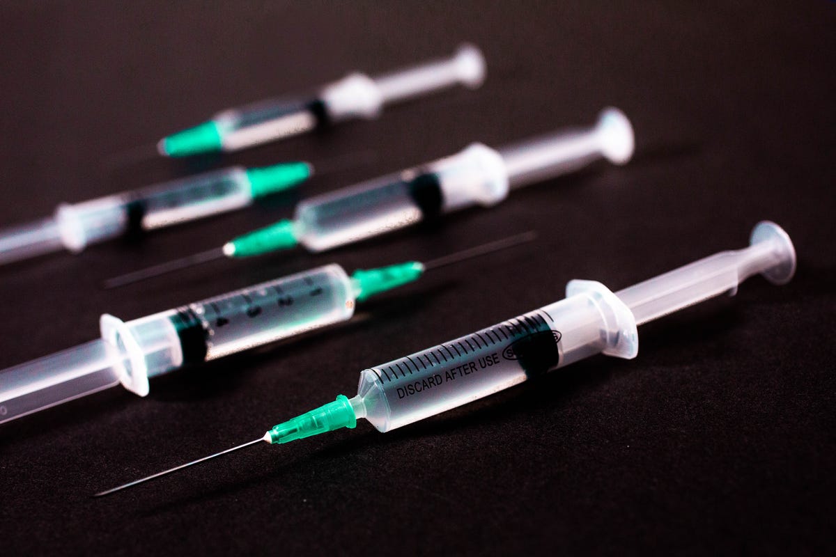 Vaccine needles arranged on a black table.