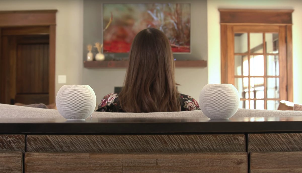 A pair of HomePods on a shelf behind a couch