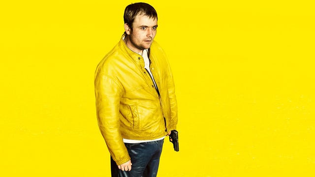 A man in a yellow jacket, holding a gun, on a yellow background