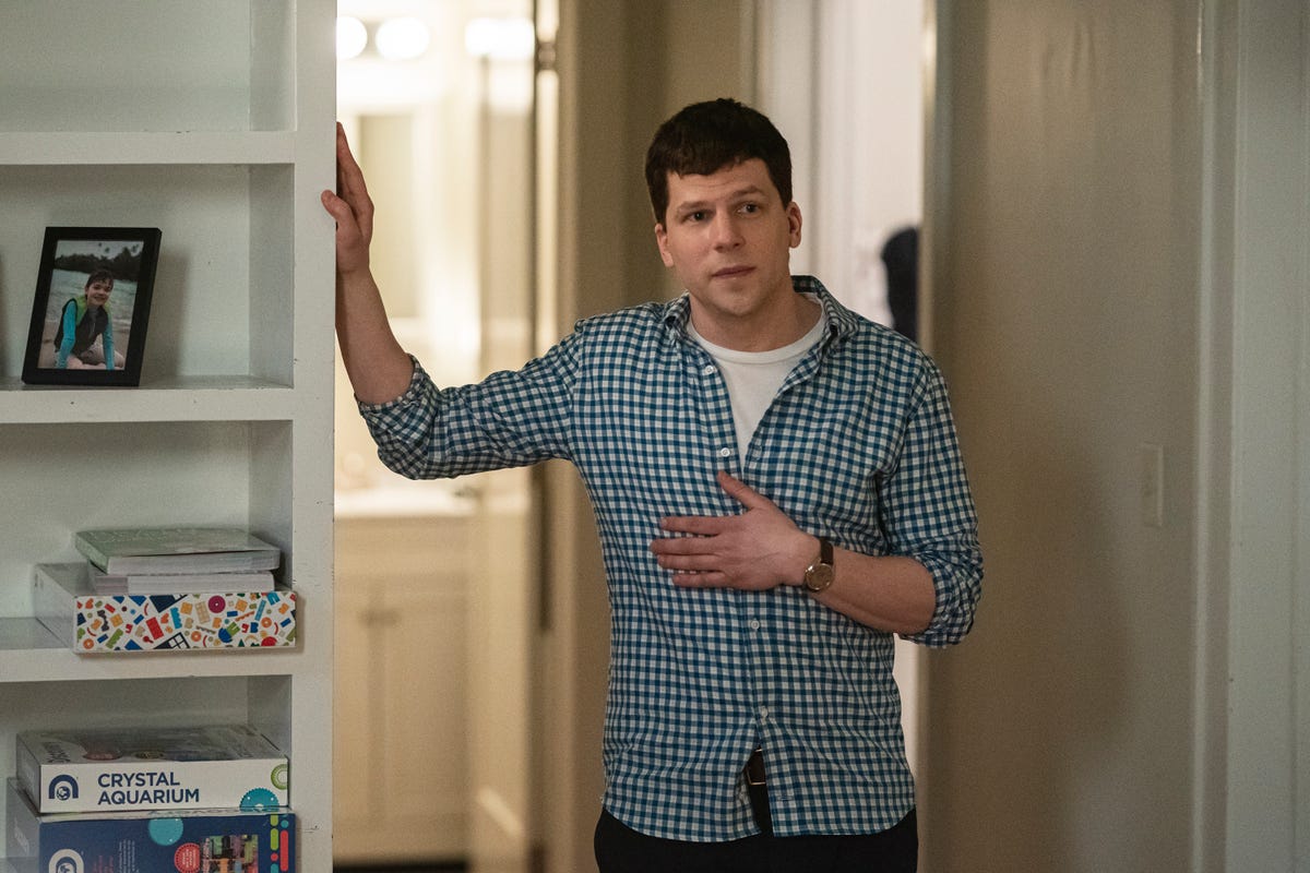 Jesse Eisenberg as Toby Fleishman stands in a doorway with one hand on the frame.