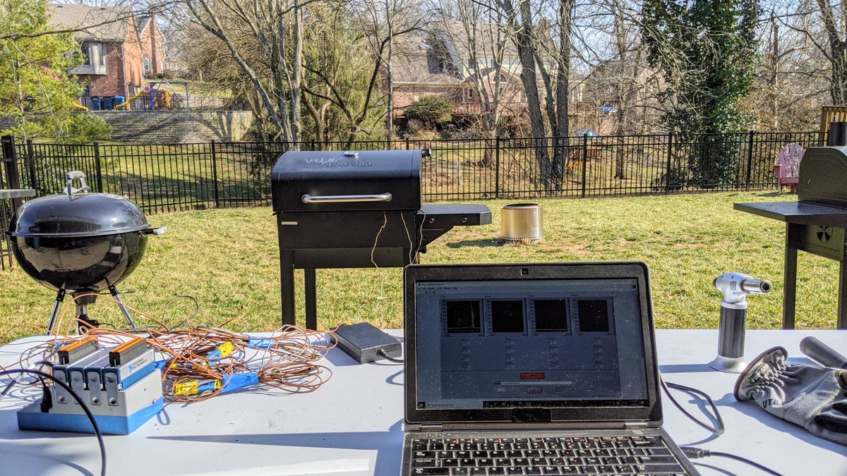 A laptop and thermocouple setup outdoors with three grills