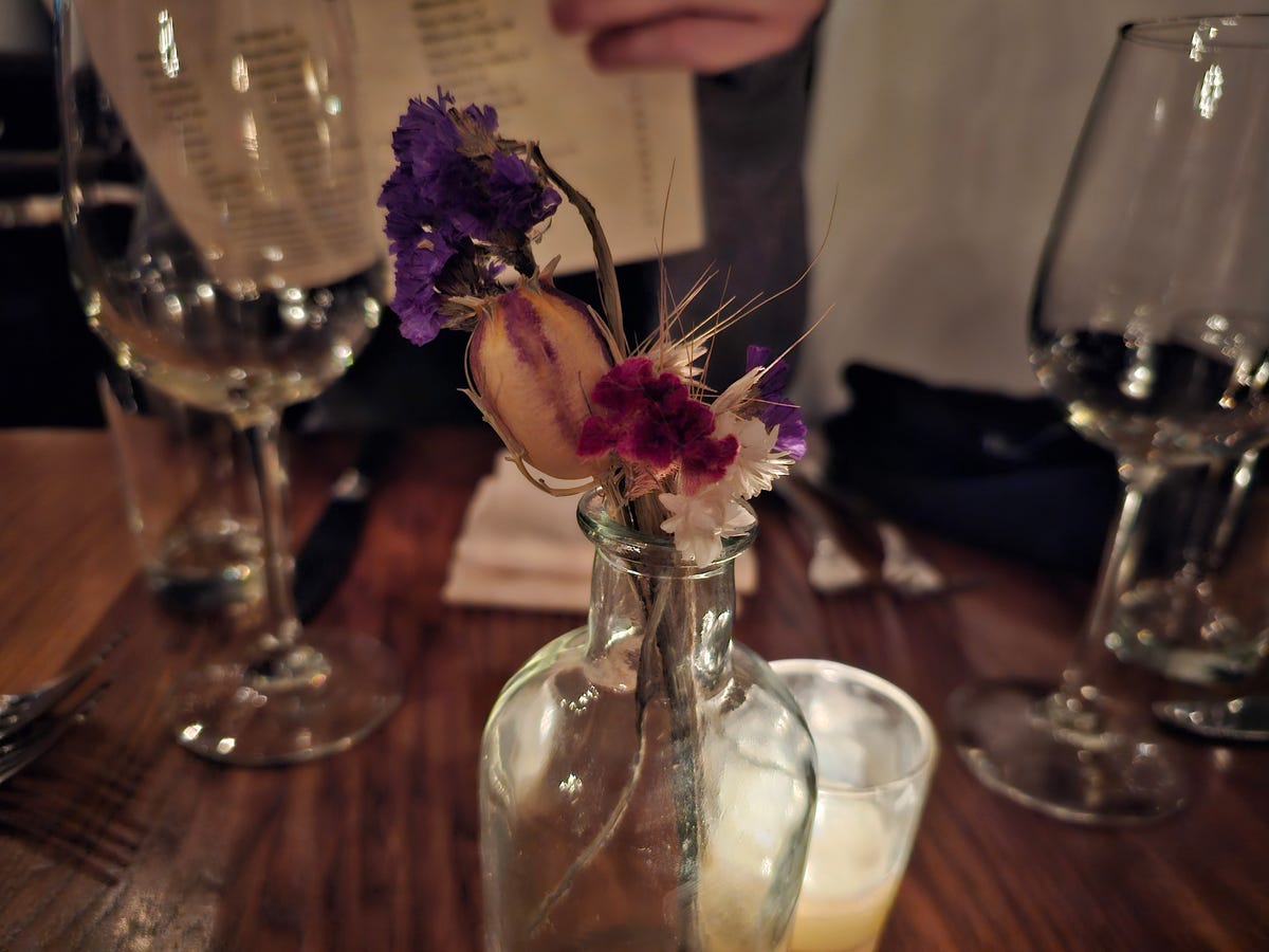 A photo of flowers in a vase in a dim restaurant taken on the Galaxy S23 Ultra