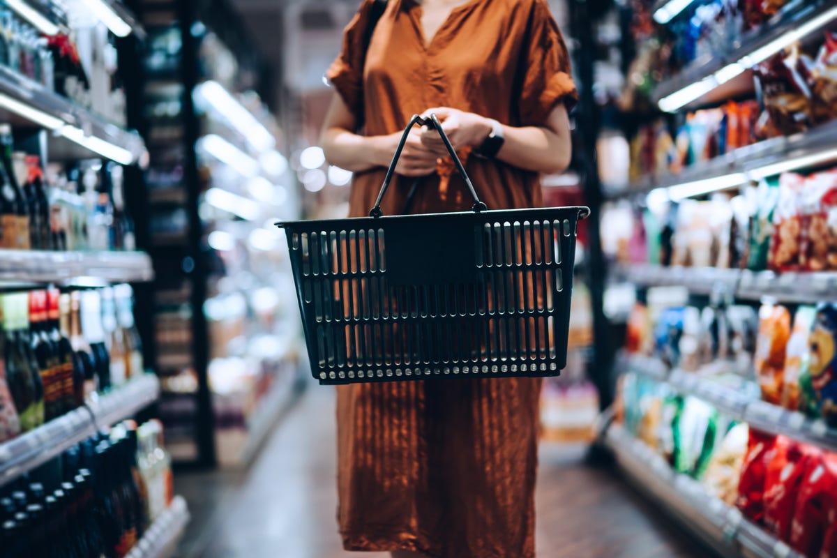 Person in a long brown dress browses a grocery store aisle.