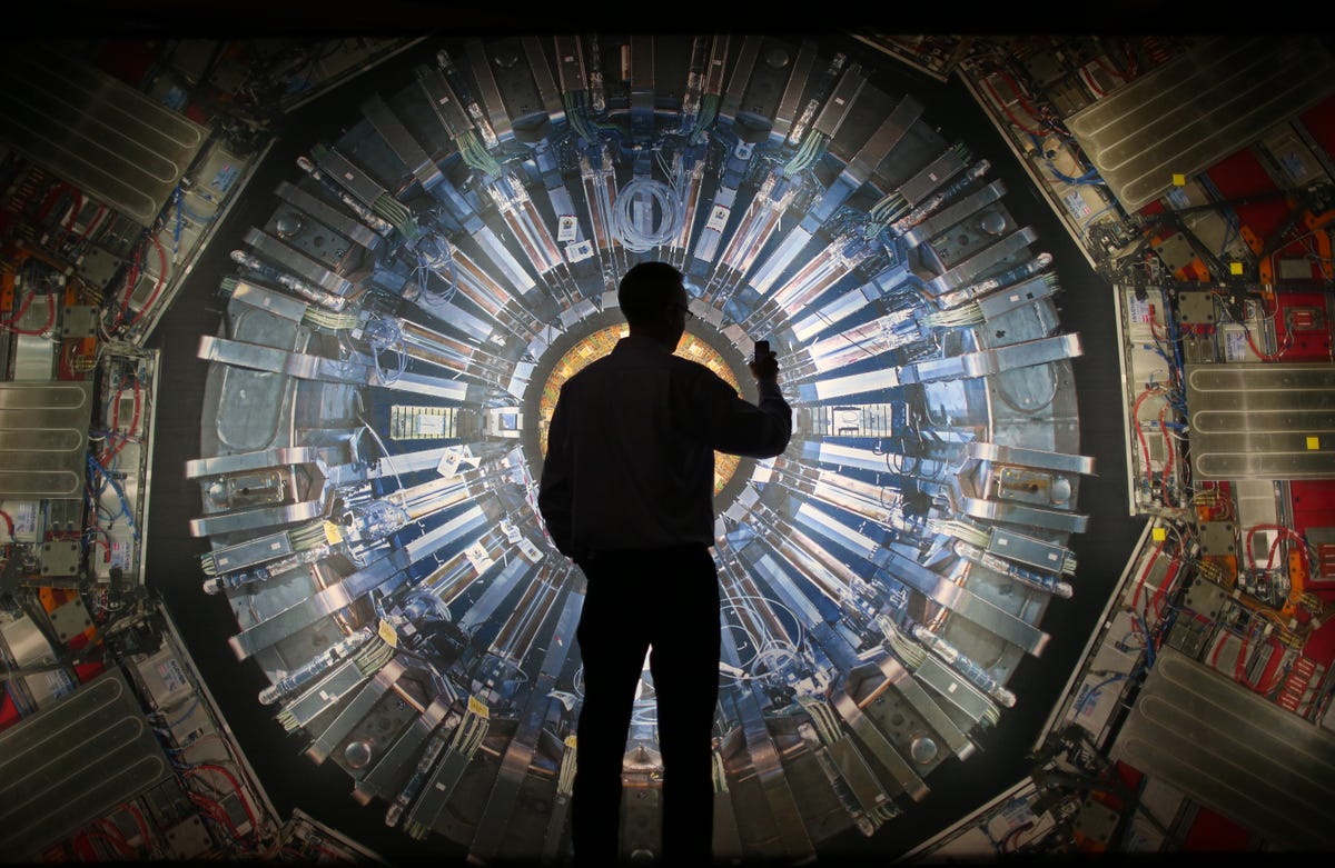A person silhouetted against an image of a portion of the Large Hadron Collider