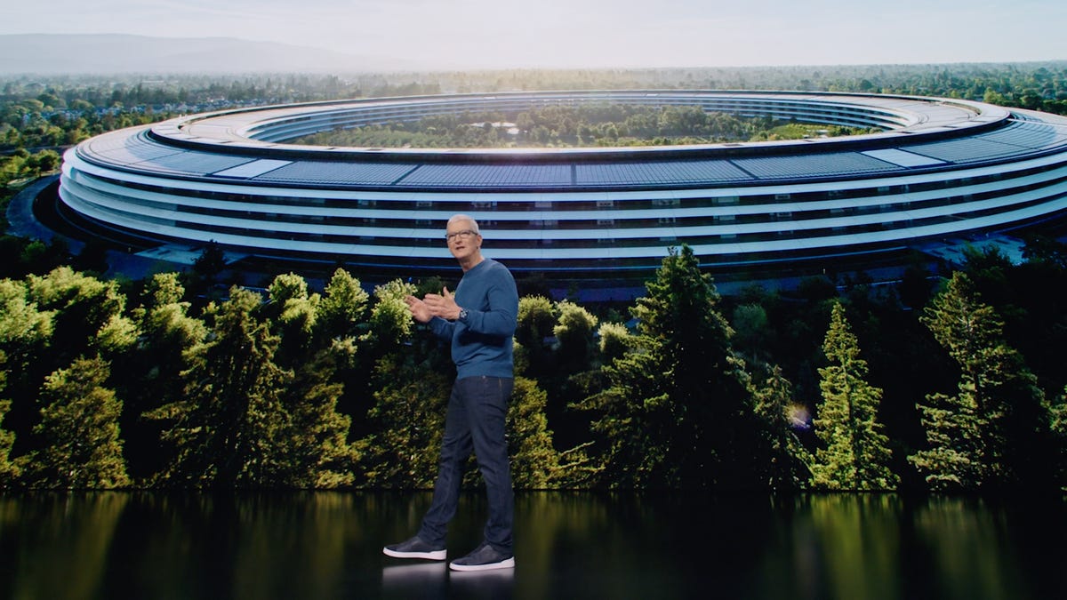 Tim Cook on stage in front of screen showing Apple's office.