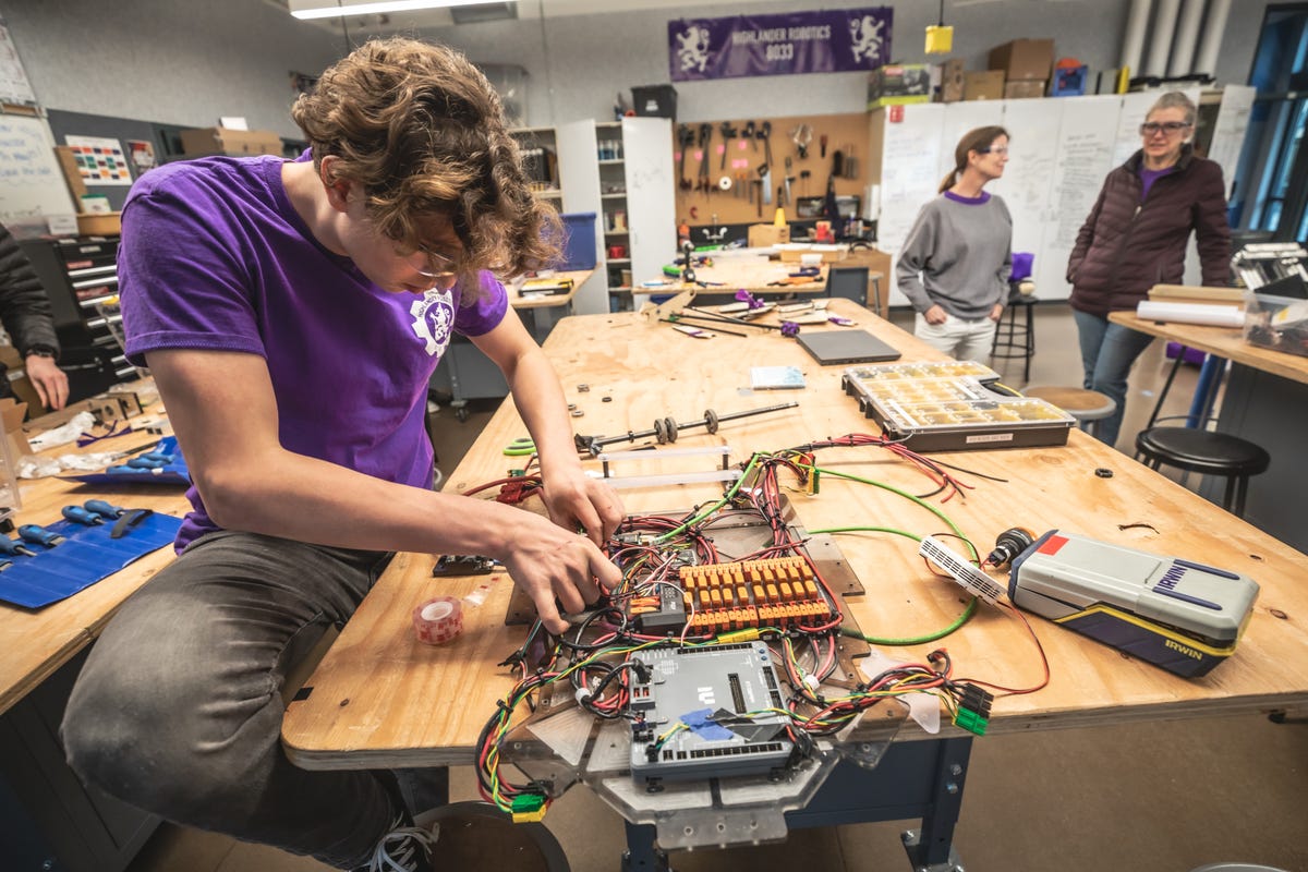 Highlander Robotics members like Vaughn Khouri labor in an engineering lab full of tools like sanding wheels and drill presses.