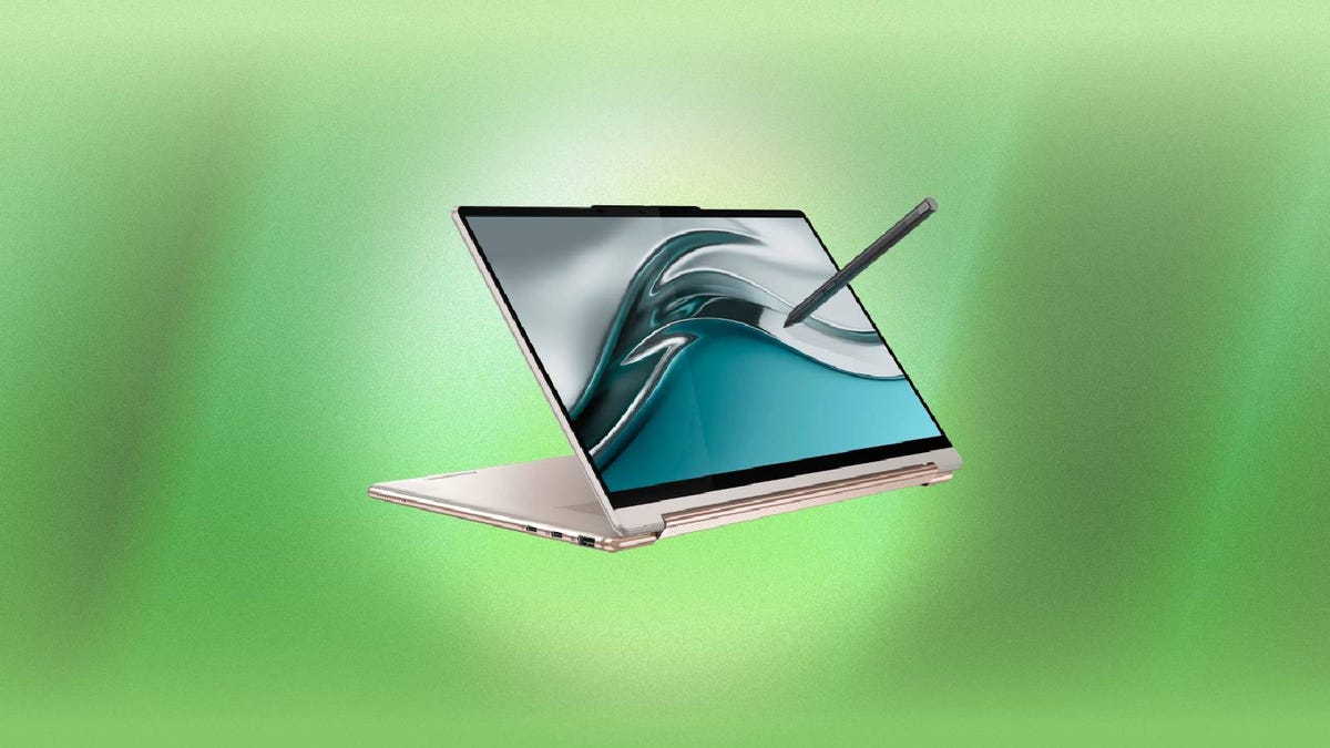 A Lenovo Yoga 9i laptop and stylus against a green background.