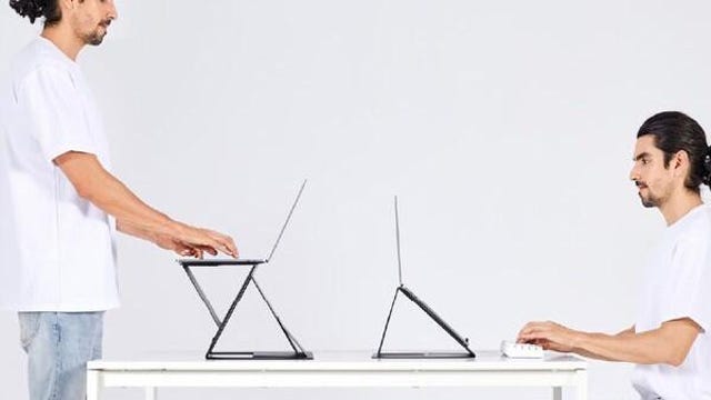 a person sitting and a person standing at a desk