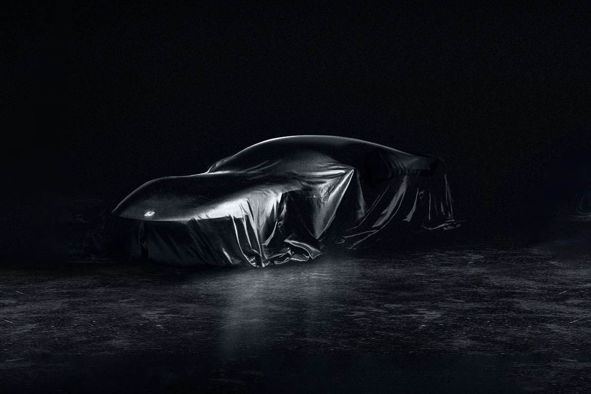 A black sports car from the side, against a dark background.