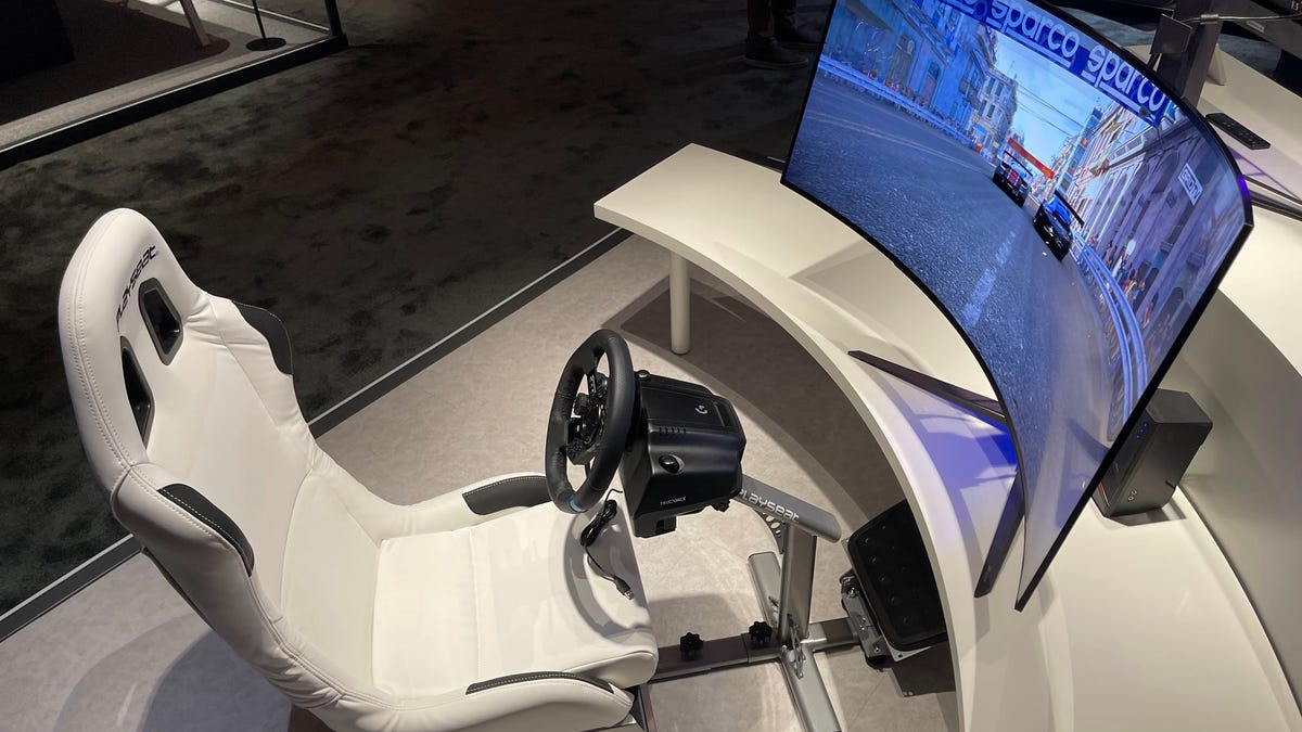 A 45-inch curved gaming monitor with a racing chair and steering wheel.