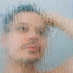 man looking at his reflection in steamy mirror