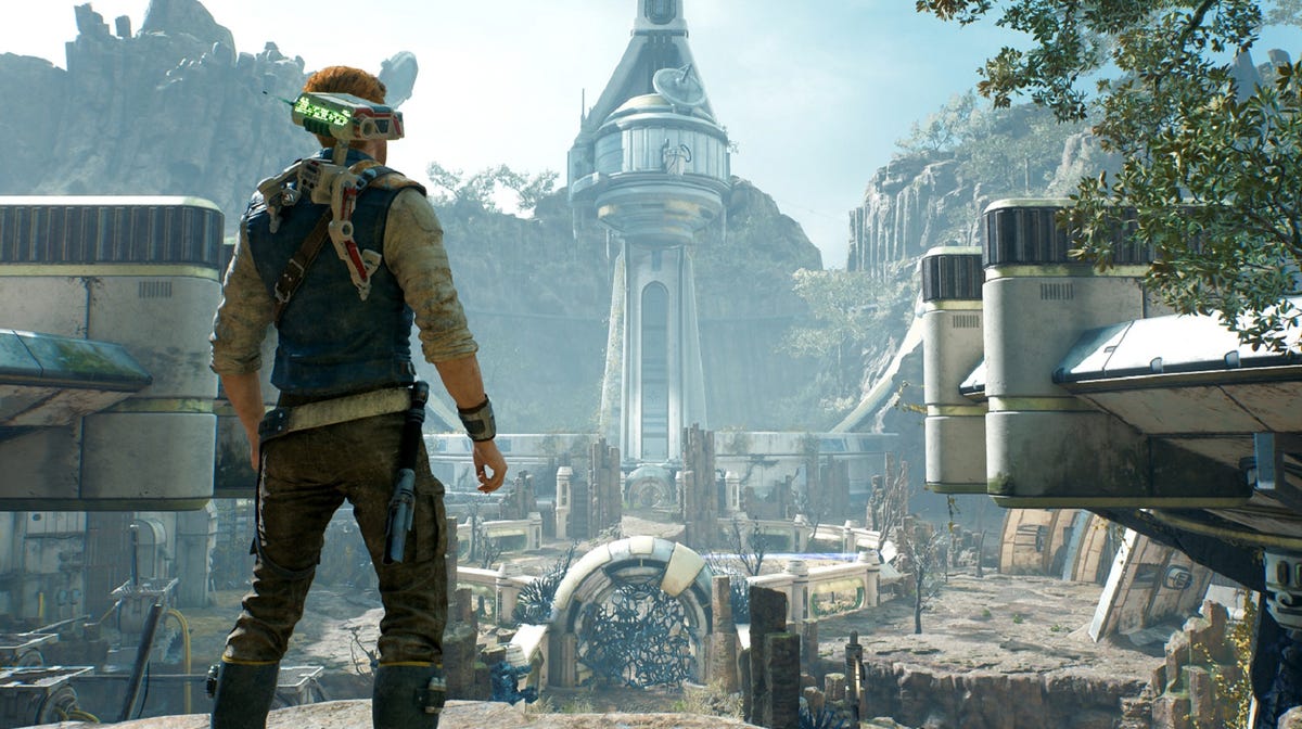 A man stands with a droid on his shoulder overlooking ruins strewn with foliage and mysterious gunk.