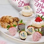 Chocolate dipped strawberries with mini cakes and cookies on a platter.