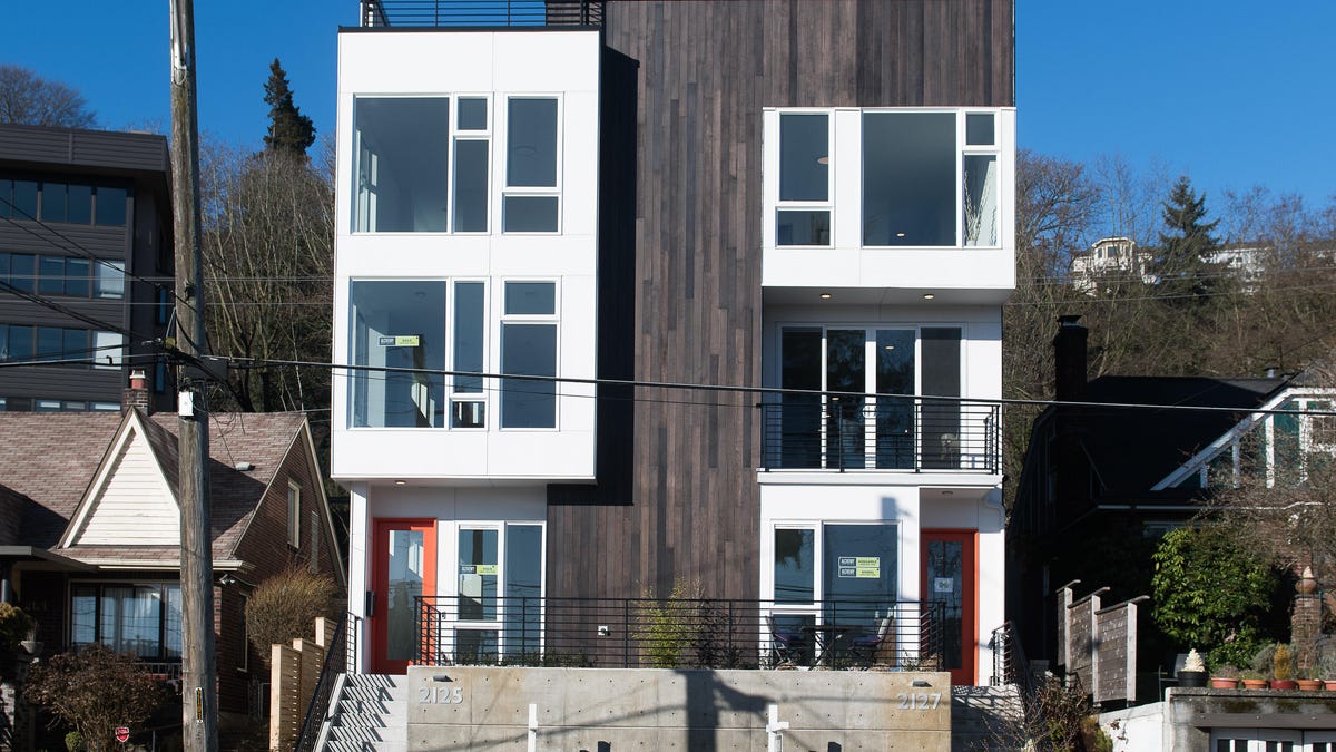 a modern three-story home with white windows and wooden cladding